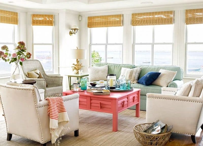 dedicated living room conversation area with coral colored square coffee table and white riveted faux leather chairs with white rattan chair and double hung picture window with bamboo blinds and coral branch table lamp