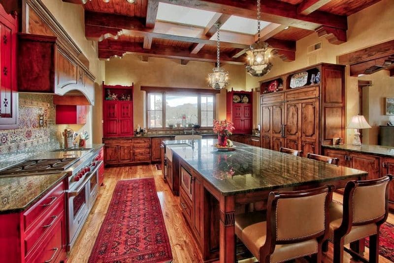 distressed red finish cabinets and custom ceramic medaillon with skylight and undermount farmhouse porcelain sink with Persian rugs