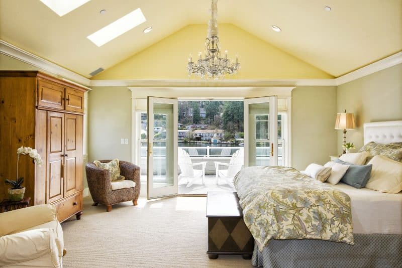 hardwood armoire and antique two-tone wooden chest with upholstered bed and skylights with crown molding and vintage crystal chandelier with rush and wood club chair