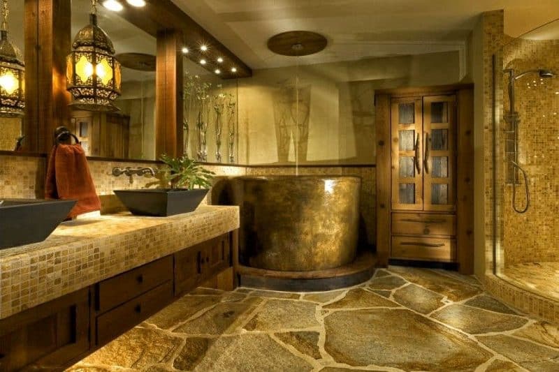 natural flagstone flooring with mosaic tiled walls and countertop with stained concrete deep tub with ceiling mounted round water fixture and solid wood bathroom armoire and vintage lattice lantern pendant light