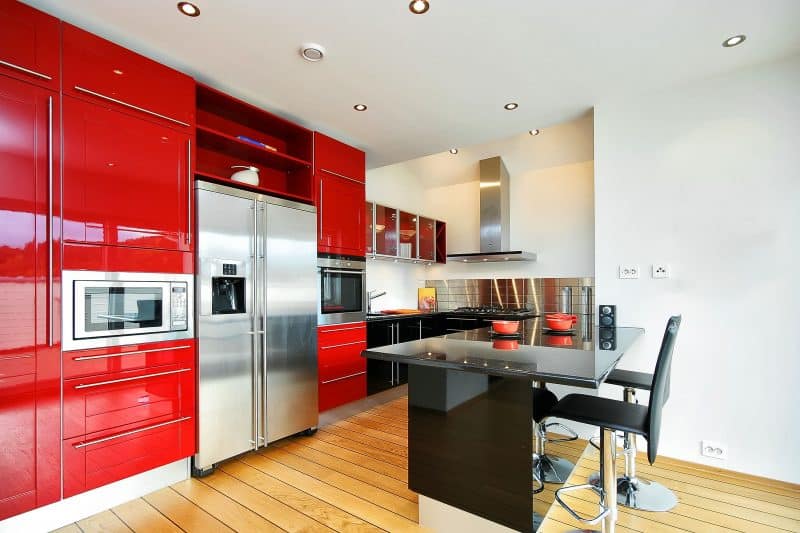red and black high gloss laminate cabinets with stamped stainless steel backsplash and swivel chairs with foot rest and wide planked light hardwood floor