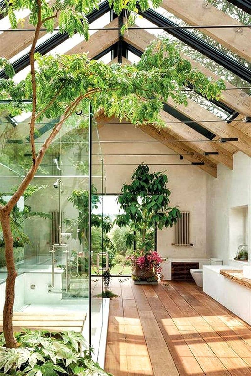 ridge skylight and large glass walk-in shower with pink bougainvillea in clay planter and natural wood slab vanity countertop with above counter sink and medium-toned hardwood wide plank flooring