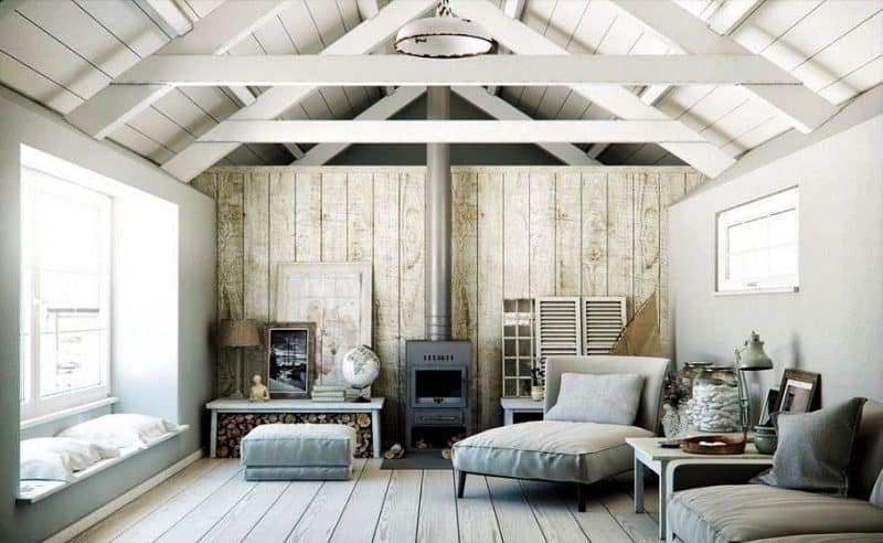 white vaulted ceiling with exposed beams and natural wood panel accent wall and bay window with seating cushions with coffee table beside fireplace used as log storage and old window doors and shutters wall displays