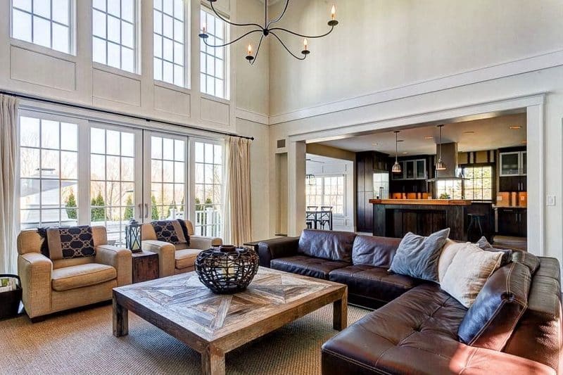 dark brown L-shaped tufted leather sofa with wood countertop calling back the earth tones in living room and reclaimed wooden coffee table with pattern and lattice wrought iron candle holder