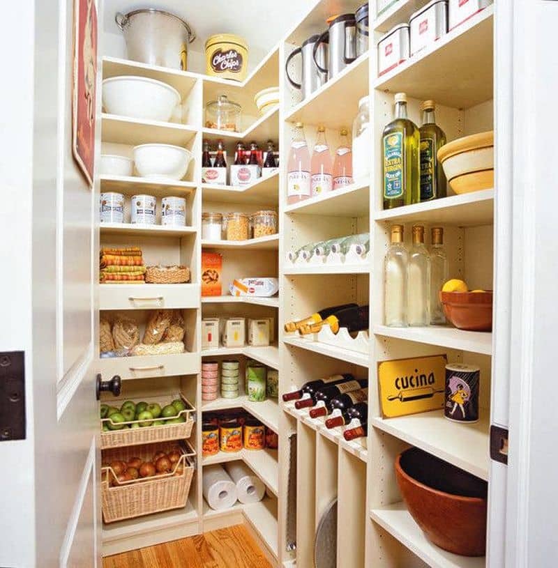 white raised paneled door with vintage poster and L-shaped corner shelves with wine storage in center shelves and cookie sheet storage with slide-out wicker baskets and yellow vintage signage on box shelf