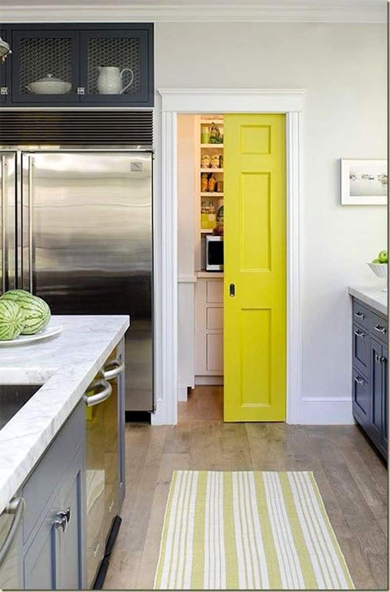 yellow pocket door to walk-in pantry with recessed panels and striped yellow area rug complementing the pantry door with white crown molding above doorway and white pantry countertop with flat panel drawers