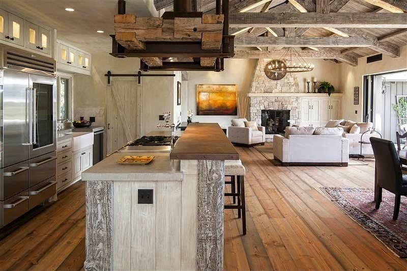 French oak flooring with whitewashed wooden beams and trusses with custom reclaimed wood partial range hood surround and whitewashed wood trims on kitchen island base calling back the beams and sliding barn door