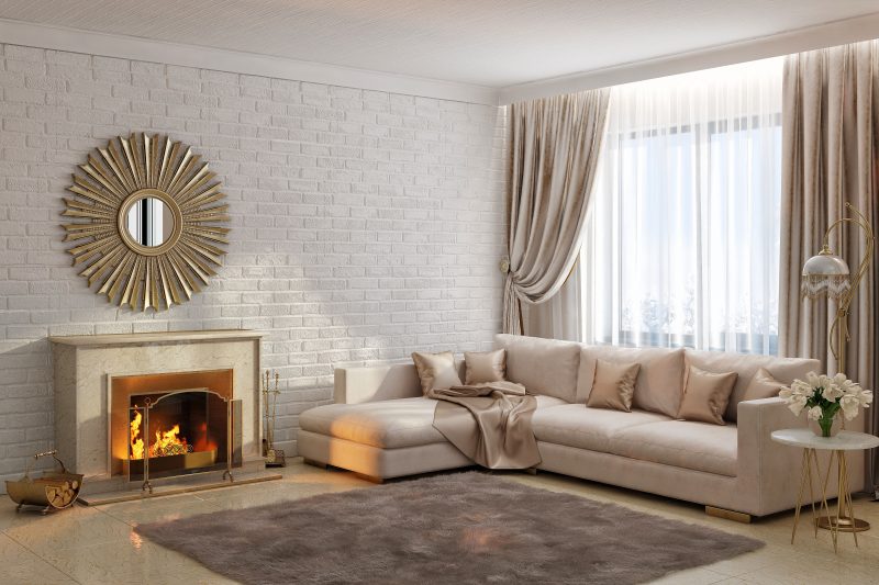 marble hearth and fireplace with copper fireplace surround and 3-panel fireplace screen with painted brick accent wall and brass firewood basket with bronze sun mirror and L-shaped sectional couch