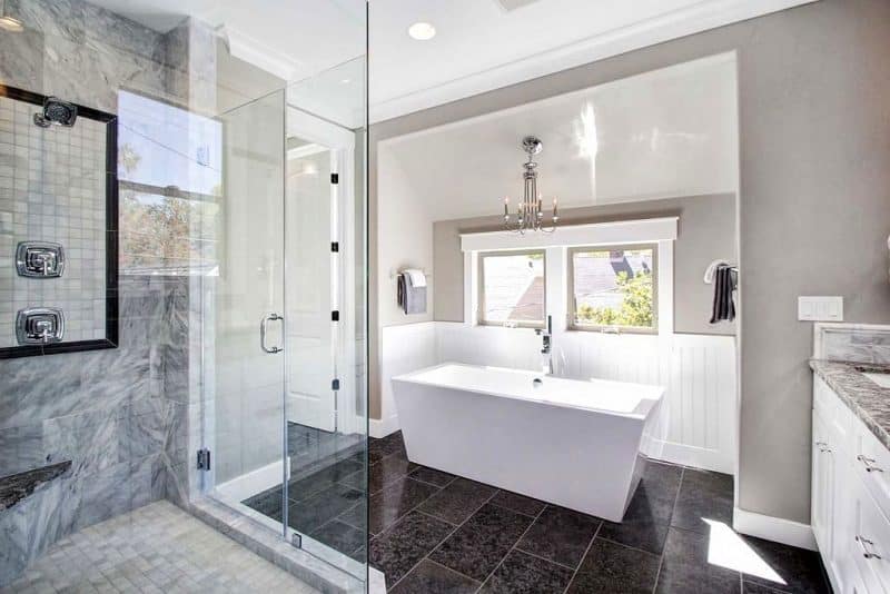 marble walk-in shower wall with gray marble mosaic tiled floor and wall accent in walk-in shower and gray marble countertop complementing the gray walls and white beadboard wainscoting with chrome faux candle chandelier