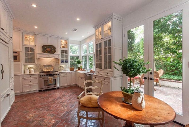 white framed full view French doors with illuminated 4-panel glass transom cabinets and built-in refrigerator with nickel birdcage handle with dentil crown molding on top cabinets and herringbone terracotta floor