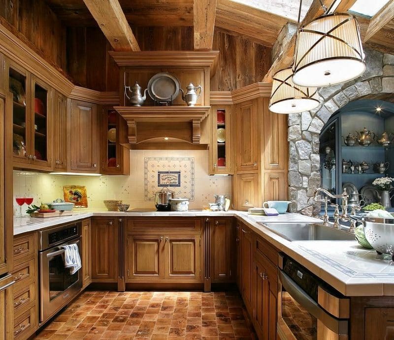 kitchen cabinets with raised panel door and chrome pulls with wooden range hood mantel and crown molding with wooden corner appliance garage and patterned porcelain tiled stove medallion backsplash with porcelain tiled floor in amber hues